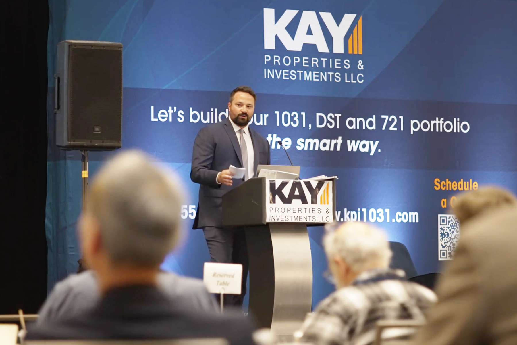 Background image of Dwight Kay speaking at a podium during a 721 Exchange UPREIT seminar