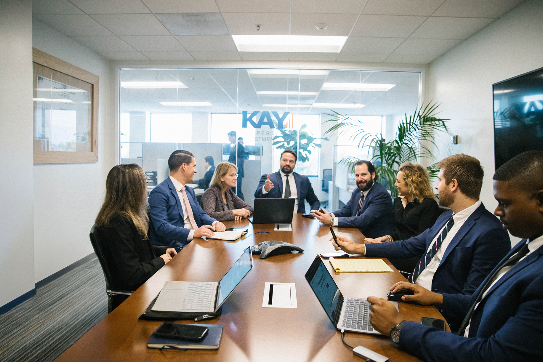 Image of Dwight Kay talking with his staff at a board room table